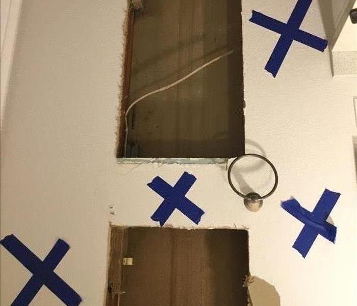 Sections of damaged wall marked with blue painter's tape